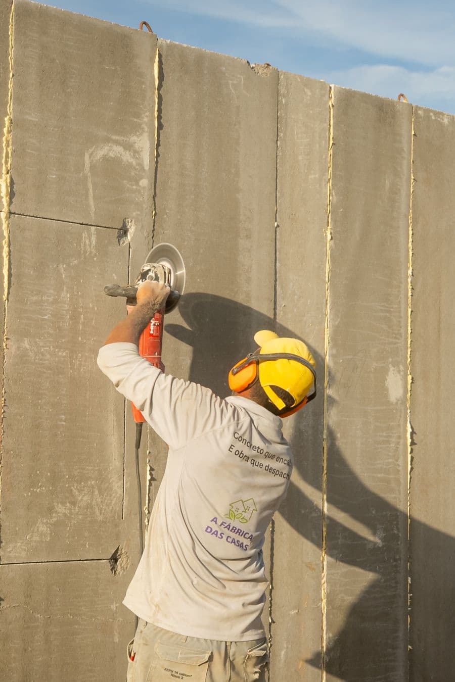 Trabalhador AFDC lixa a superfície de um painel de concreto.