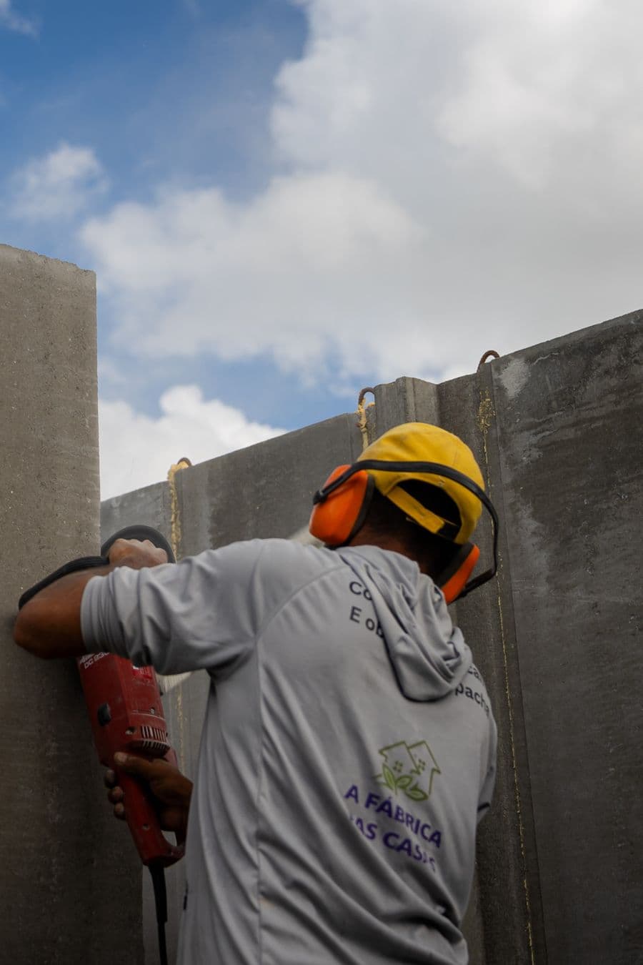 Trabalhador AFDC perfura um painel de concreto pré-moldado.