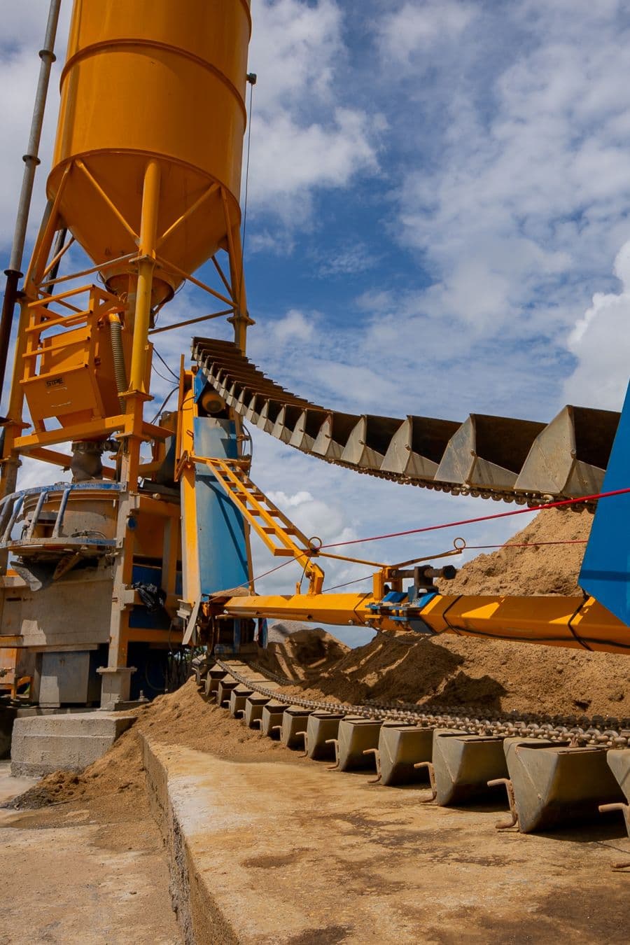Usina de concreto com silo amarelo e esteiras transportadoras.