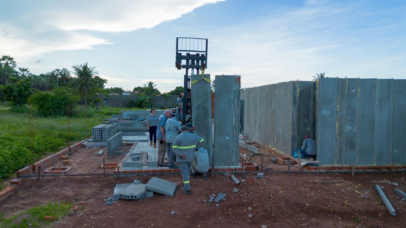 Empilhadeira içando painel de concreto pré-moldado em obra modular.