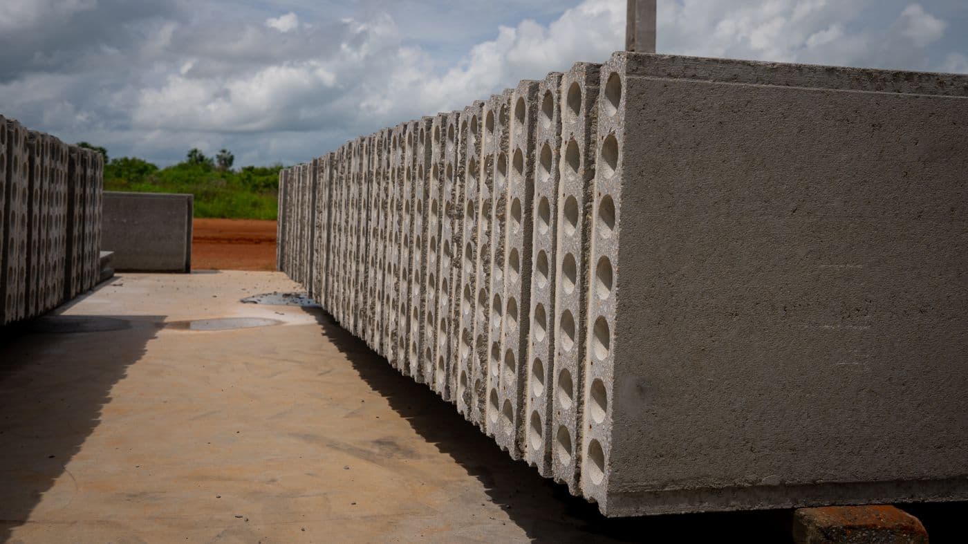 Painéis alveolares de concreto com seção vazada estocados no pátio.